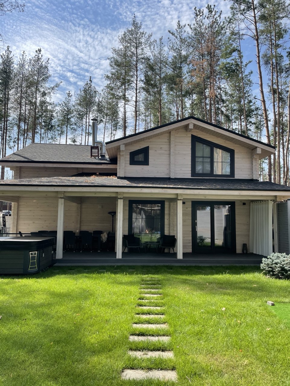 A wood home with dark-framed windows surrounded by tall pine trees