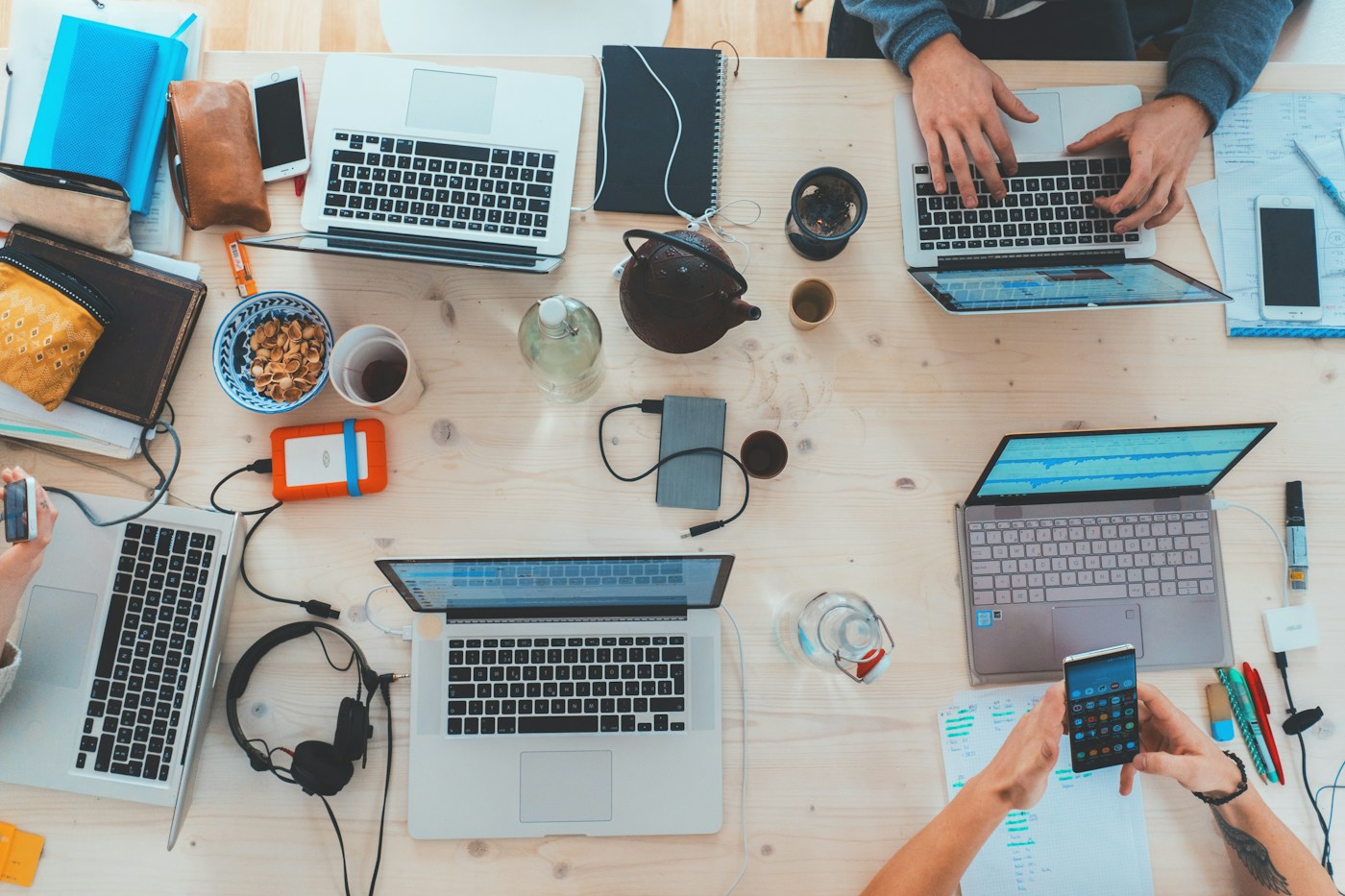 People collaborating with laptops around a work table